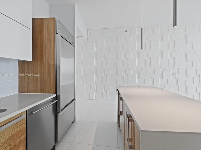 kitchen featuring white cabinets, built in refrigerator, and light tile patterned flooring