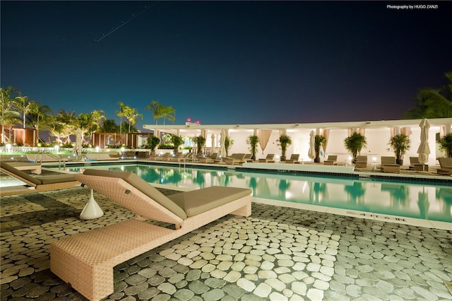 pool at twilight with a patio area