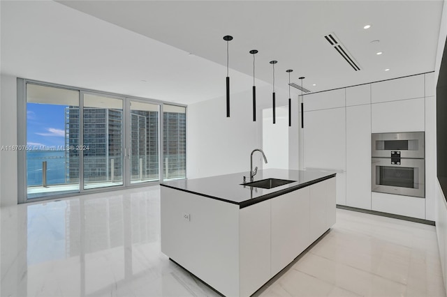 kitchen with sink, decorative light fixtures, white cabinetry, stainless steel double oven, and a water view