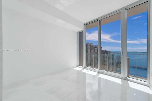 unfurnished room with a wall of windows and a water view