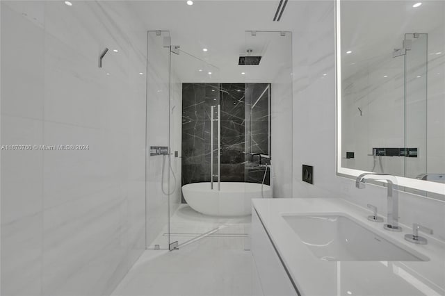 bathroom featuring tile walls, vanity, and separate shower and tub