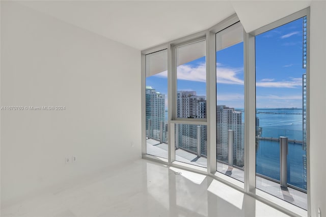 spare room featuring floor to ceiling windows, a water view, and a wealth of natural light