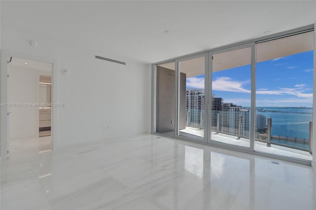 spare room featuring a water view and expansive windows