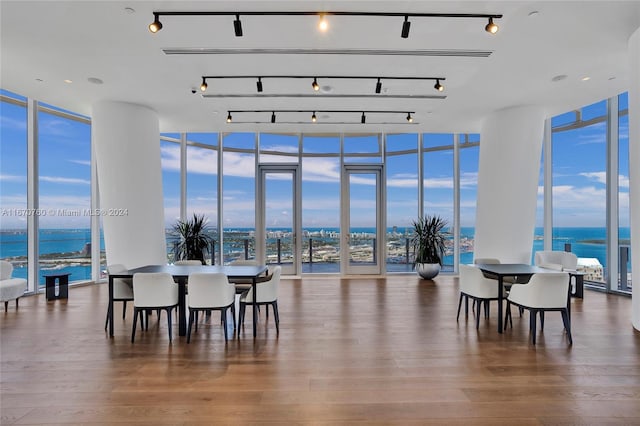 dining room featuring floor to ceiling windows, a water view, and hardwood / wood-style floors