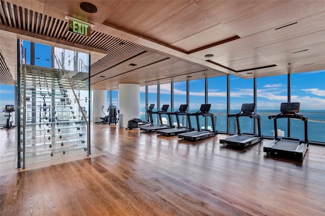 gym with wood-type flooring, a water view, floor to ceiling windows, and wood ceiling