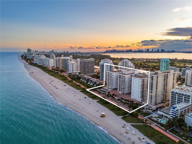 aerial view at dusk with a view of the beach and a water view