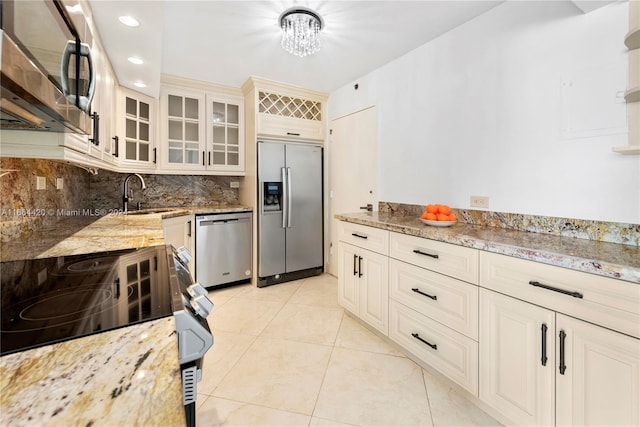 kitchen with light stone countertops, appliances with stainless steel finishes, backsplash, and sink