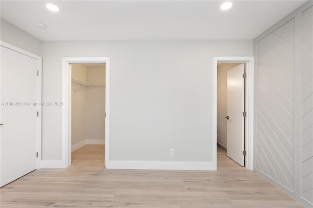 unfurnished bedroom with light hardwood / wood-style flooring, a walk in closet, and a closet