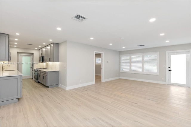 unfurnished living room with sink and light hardwood / wood-style flooring