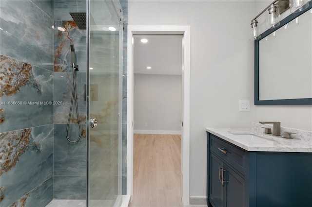 bathroom featuring hardwood / wood-style flooring, vanity, and a tile shower