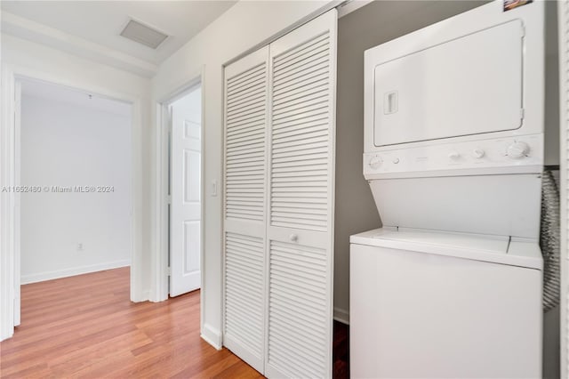 clothes washing area featuring light hardwood / wood-style floors and stacked washing maching and dryer