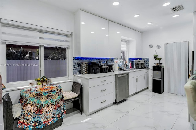 kitchen with stainless steel dishwasher, white cabinetry, sink, and tasteful backsplash