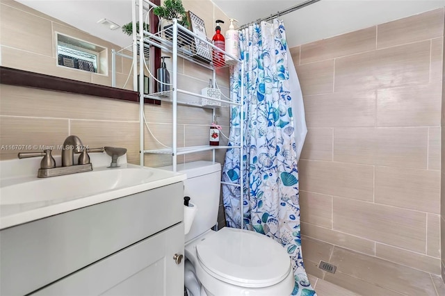 bathroom with tile walls, curtained shower, vanity, and toilet