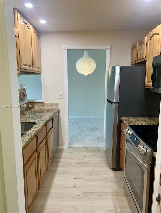 kitchen with stainless steel appliances, light hardwood / wood-style flooring, light stone counters, and sink