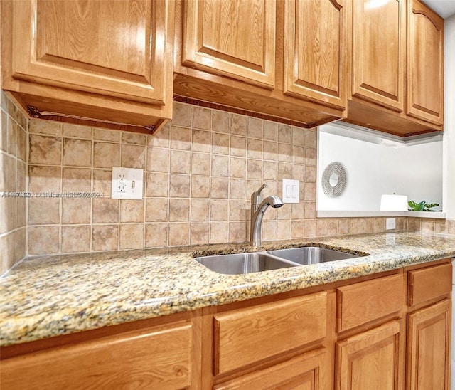 kitchen with light stone counters, sink, and backsplash