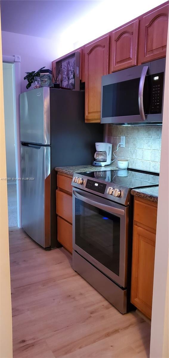 kitchen with decorative backsplash, appliances with stainless steel finishes, and light hardwood / wood-style flooring