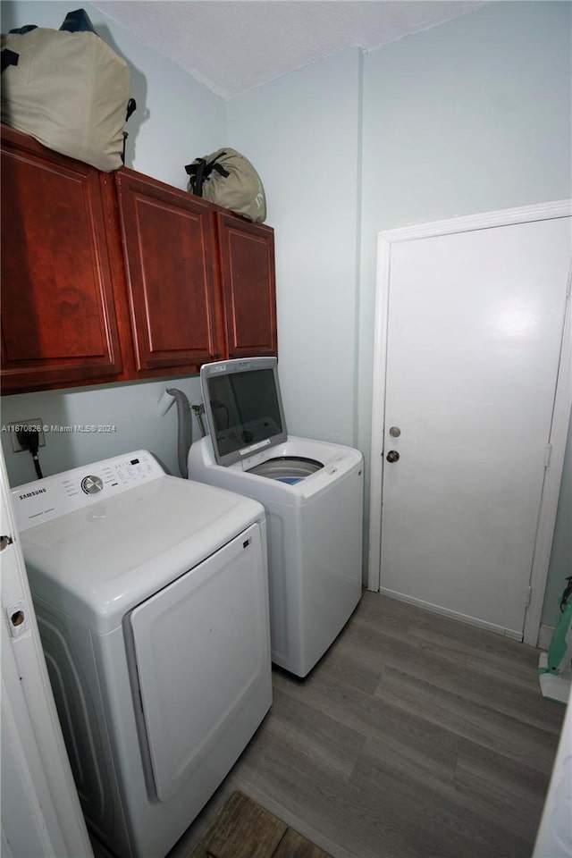 laundry room featuring separate washer and dryer, cabinets, and light hardwood / wood-style flooring