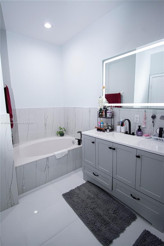 bathroom featuring tile patterned floors, tiled bath, and vanity