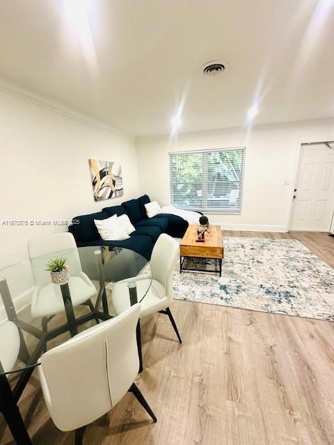 living room with light wood-type flooring and crown molding