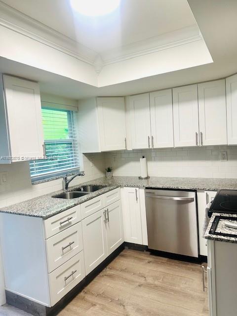 kitchen with dishwasher, a raised ceiling, sink, white cabinets, and light wood-type flooring