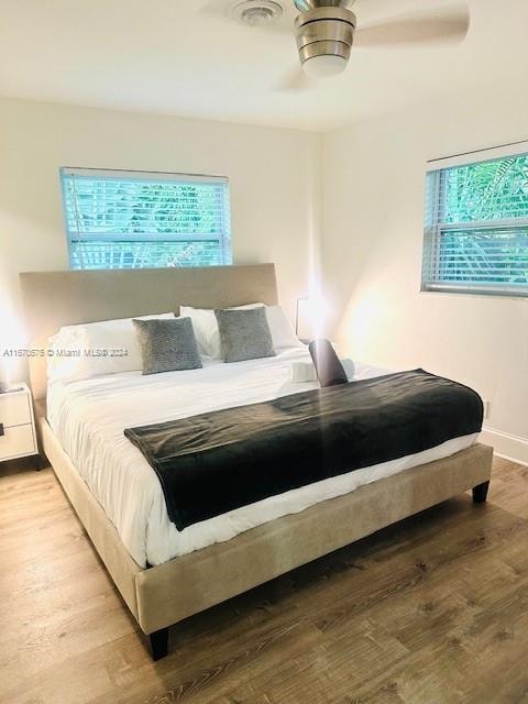 bedroom with light wood-type flooring, multiple windows, and ceiling fan