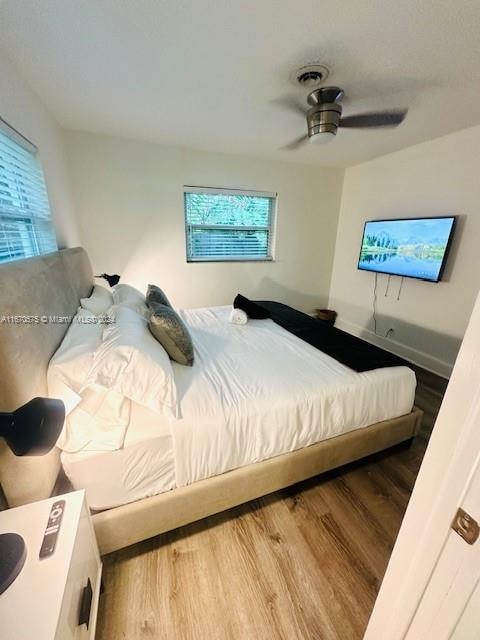 bedroom with multiple windows, hardwood / wood-style flooring, and ceiling fan