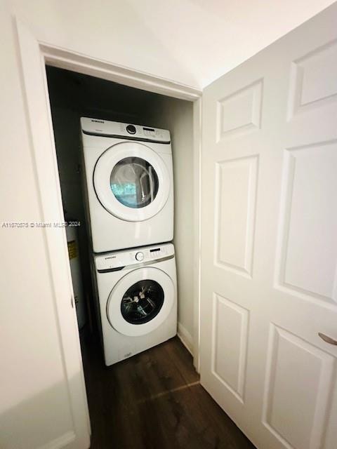 laundry area with dark hardwood / wood-style floors and stacked washer / dryer