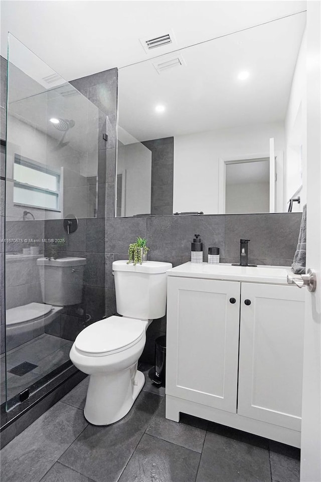 bathroom with tile patterned floors, tiled shower, toilet, vanity, and decorative backsplash