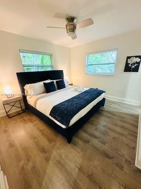 bedroom with hardwood / wood-style floors, multiple windows, and ceiling fan