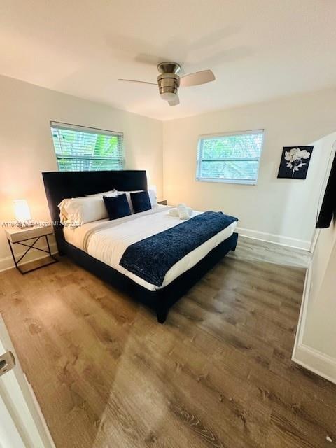 bedroom with multiple windows, ceiling fan, and wood-type flooring