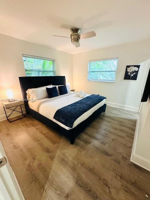 bedroom with ceiling fan, multiple windows, and hardwood / wood-style flooring