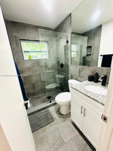 bathroom featuring tiled shower, vanity, and toilet