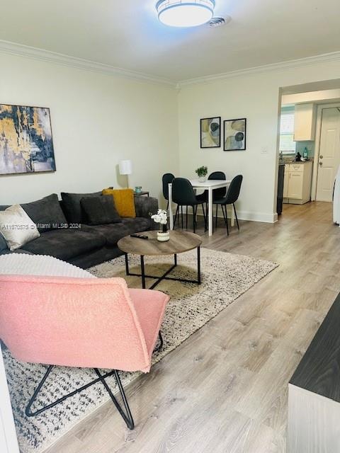 living room with crown molding and light hardwood / wood-style floors