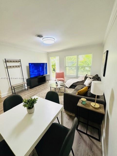 living room with crown molding and light wood-type flooring