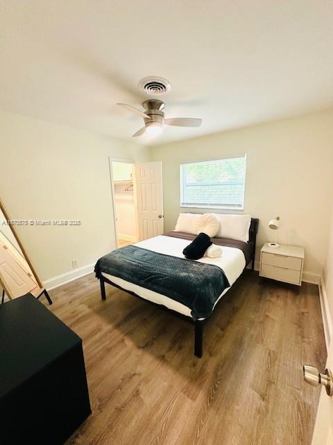 bedroom with a walk in closet, ceiling fan, wood-type flooring, and a closet