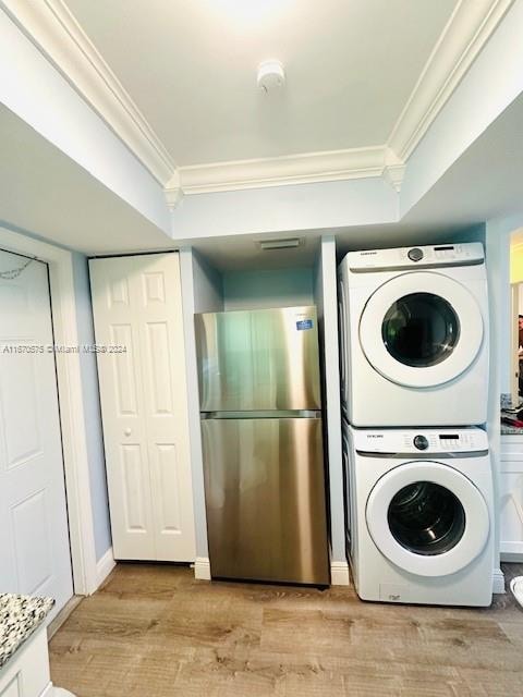 laundry area with light hardwood / wood-style flooring, stacked washer / drying machine, and crown molding