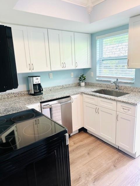 kitchen with white cabinets, stainless steel dishwasher, black range with electric cooktop, a tray ceiling, and light hardwood / wood-style flooring