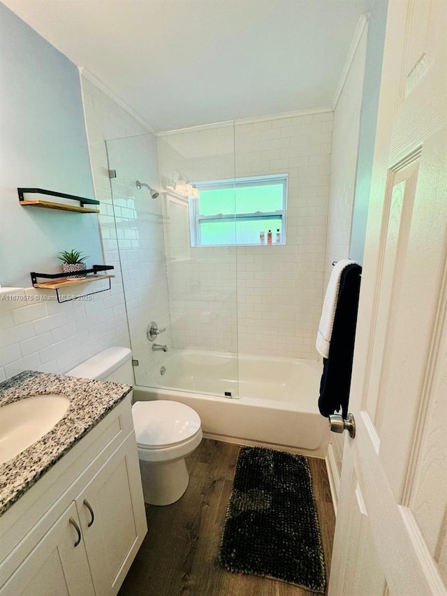 full bathroom with tiled shower / bath, wood-type flooring, vanity, toilet, and crown molding