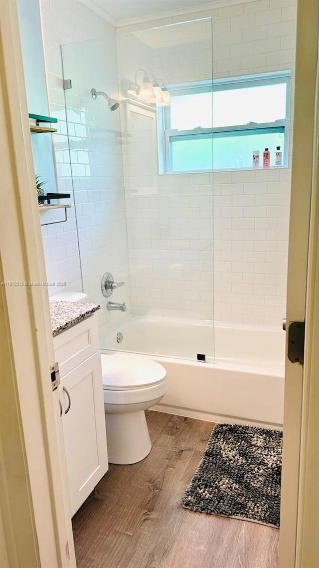 full bathroom with toilet, hardwood / wood-style floors, tiled shower / bath combo, vanity, and plenty of natural light