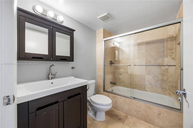 full bathroom featuring enclosed tub / shower combo, vanity, tile patterned flooring, and toilet