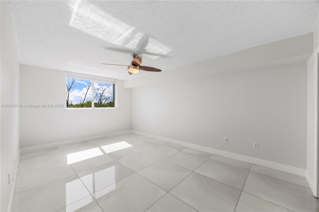 tiled spare room featuring a textured ceiling and ceiling fan