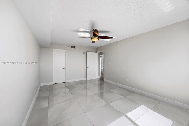 unfurnished bedroom with ceiling fan, light tile patterned floors, and a textured ceiling