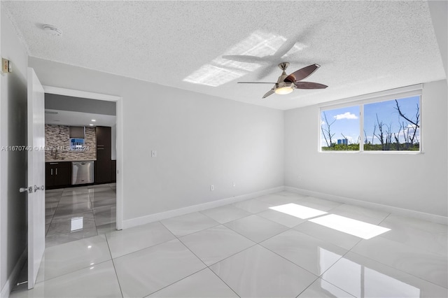 empty room with a textured ceiling, ceiling fan, and tile patterned floors