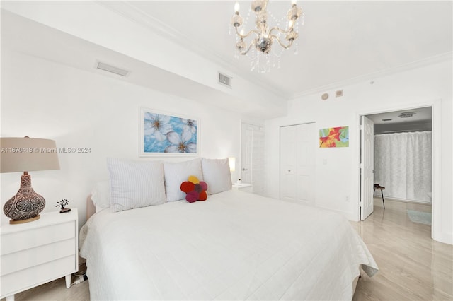 bedroom featuring light hardwood / wood-style floors, a closet, ornamental molding, and a chandelier