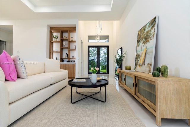 living room with a raised ceiling, light tile patterned flooring, and a notable chandelier