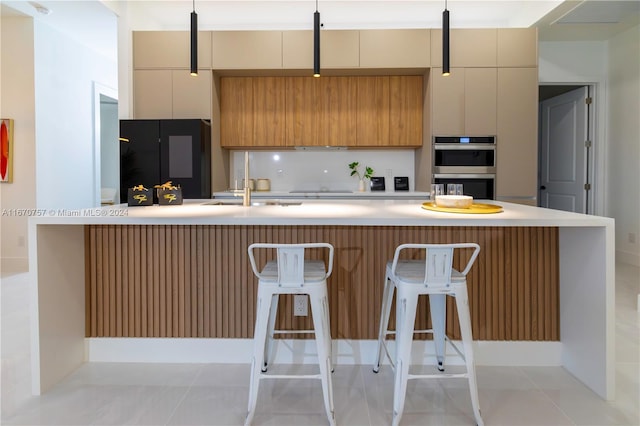 kitchen with sink, light tile patterned floors, double oven, a breakfast bar area, and black refrigerator