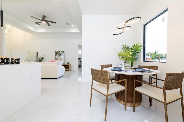 dining area featuring ceiling fan and a tray ceiling