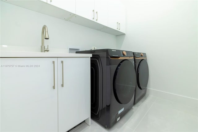 laundry room featuring light tile patterned flooring, sink, cabinets, and washer and clothes dryer