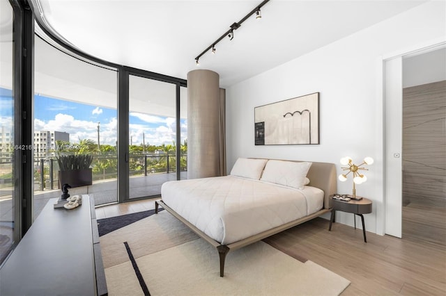 bedroom featuring light hardwood / wood-style floors, track lighting, and access to exterior