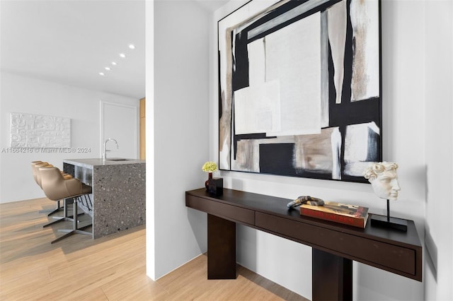 home office with light hardwood / wood-style floors and sink